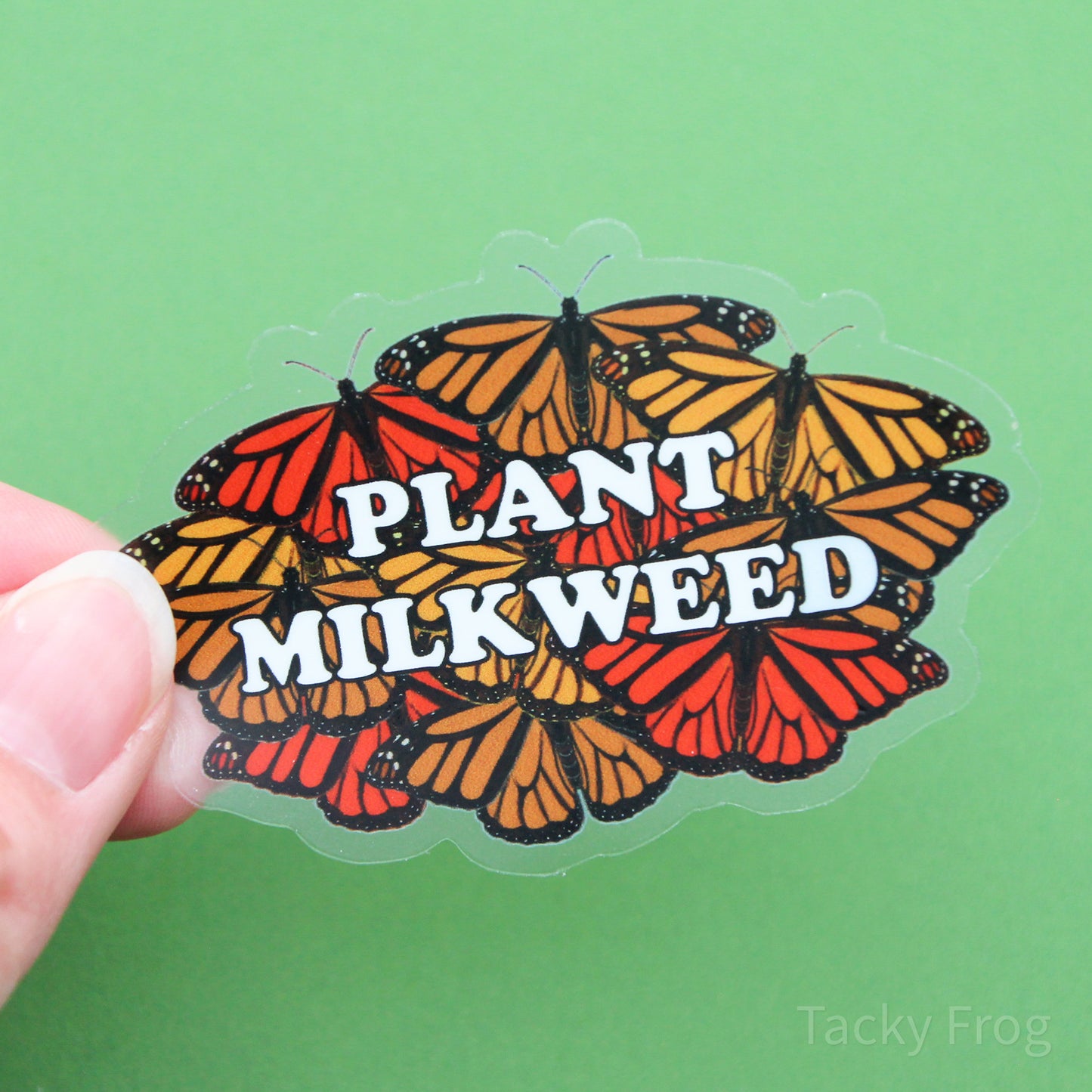 A clear vinyl sticker depicting a design made up of monarch butterflies behind white text that reads "plant milkweed".