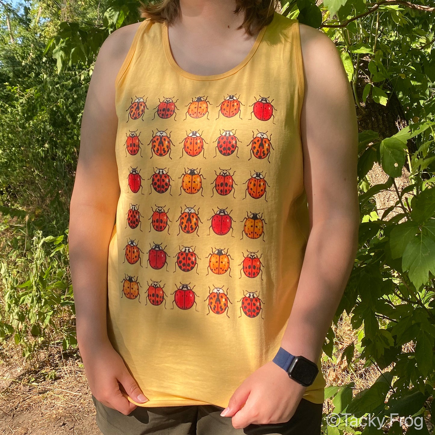 A woman wearing the unisex ladybug tank top in the "squash" color.