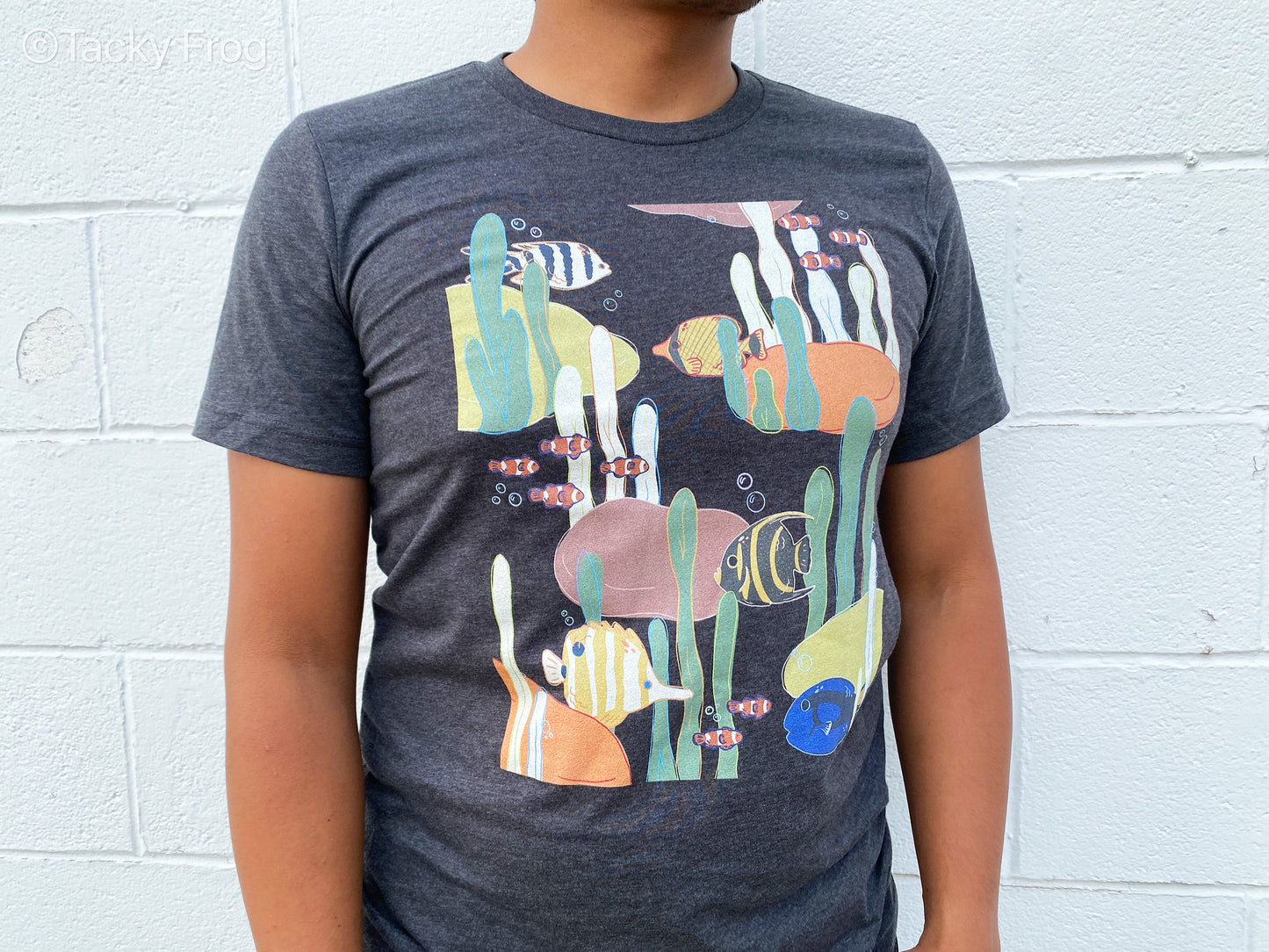 Another view of the coral reef-inspired t-shirt. Depicted on the shirt are clown fish, butterfly fish, a blue tang, and more.