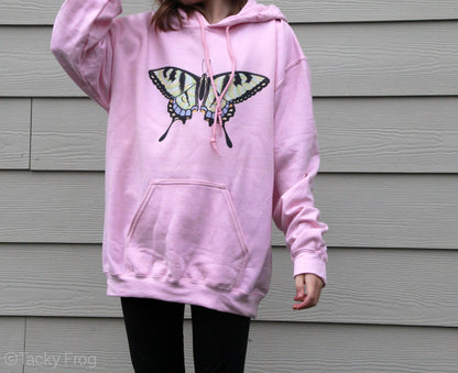 A girl wearing a pink hoodie with a swallowtail butterfly on it.