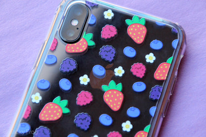 A clear phone case with a mixed berries and daisies pattern. It is shown on an iPhone X.