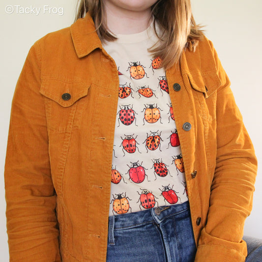 A woman wearing a ladybug shirt under a mustard yellow jacket.