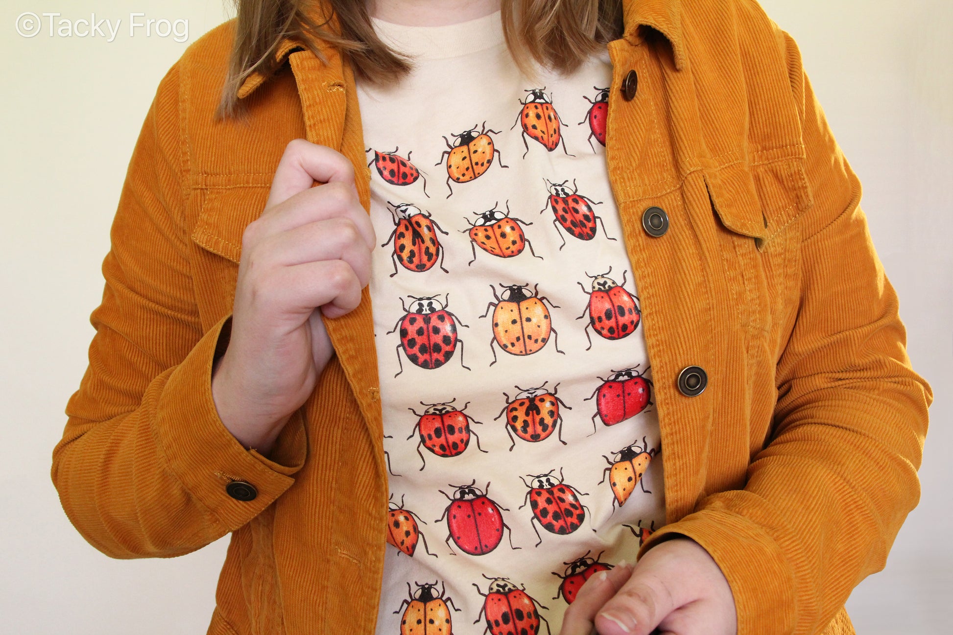 A close-up view of the ladybug shirt worn under a mustard jacket.