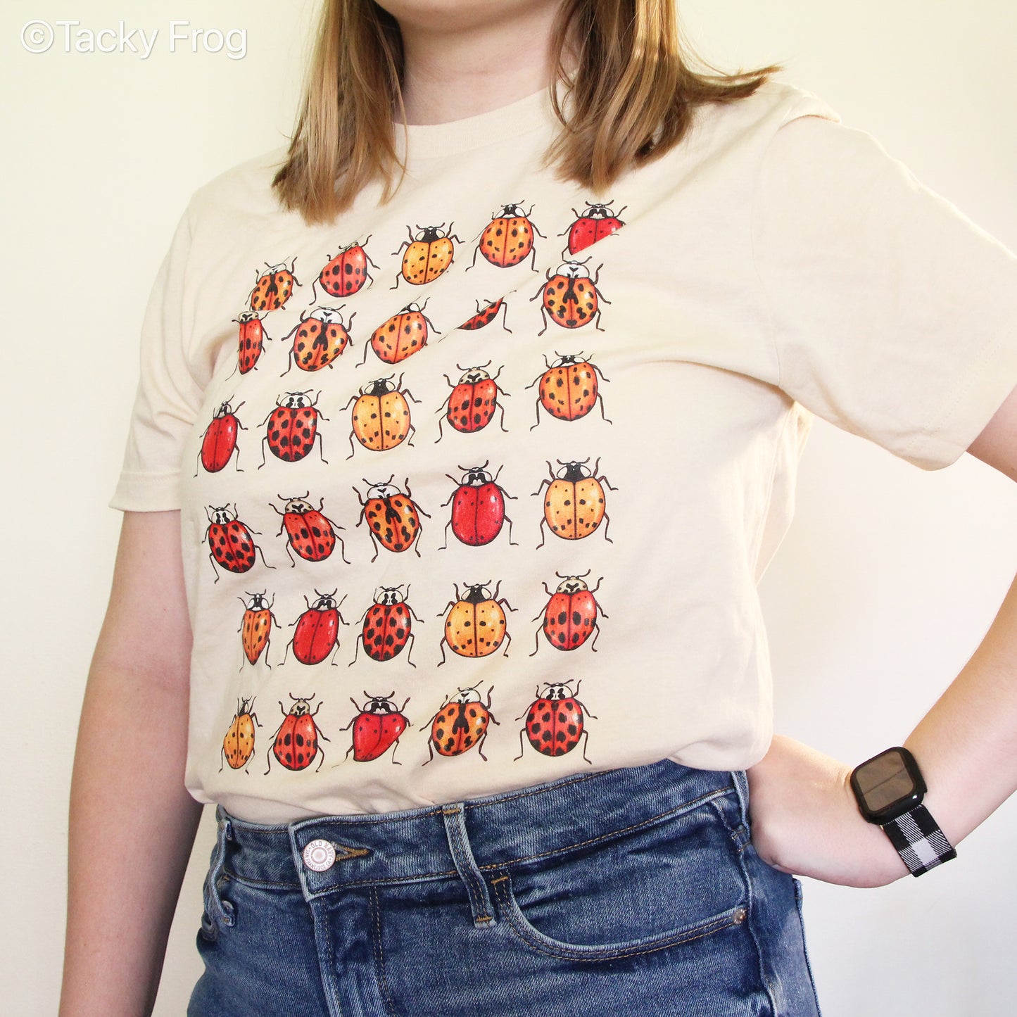 A woman wearing a soft cream-colored ladybug t-shirt tucked in.