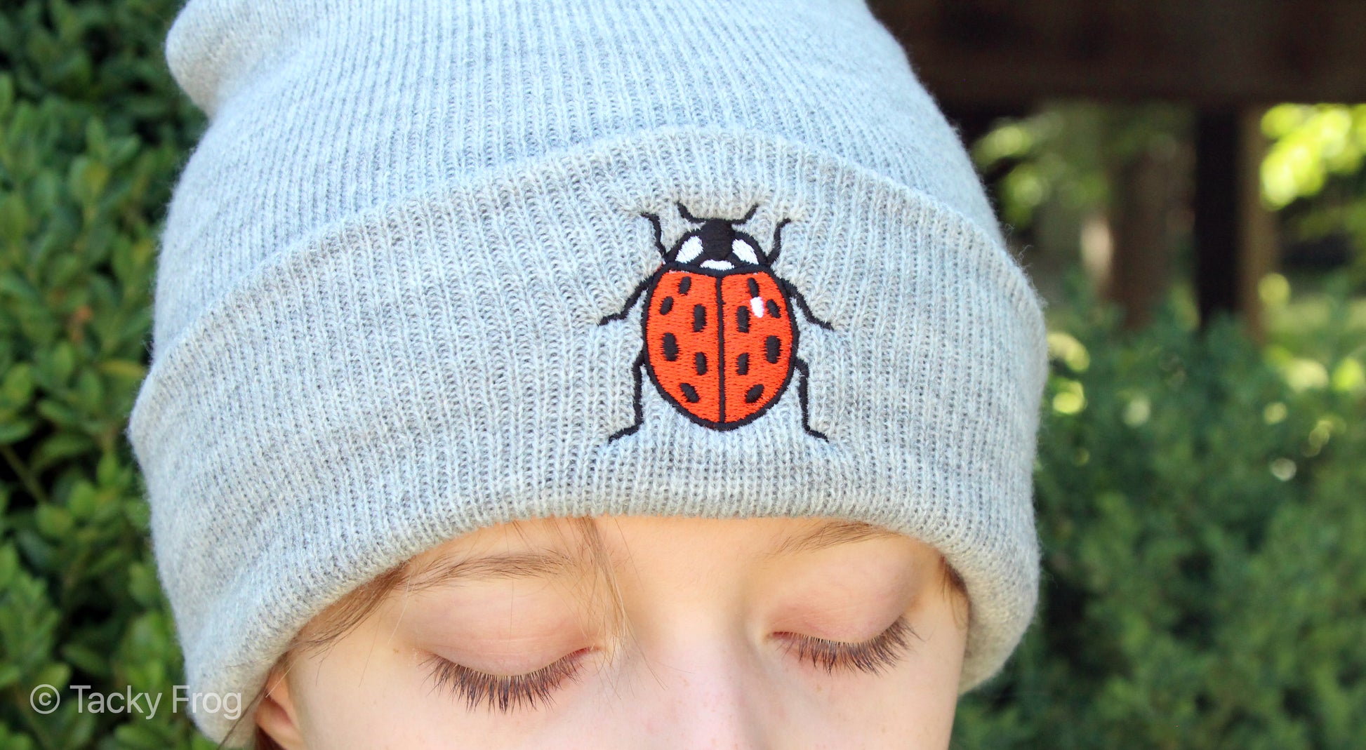 A young woman wearing the heather grey ladybug beanie.