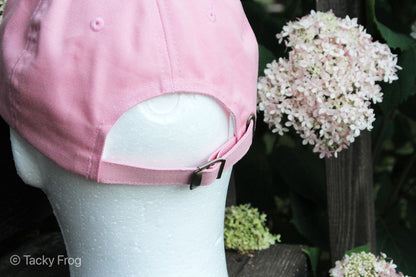 A closeup of a buckle on the back of the strawberries and bees dad hat.