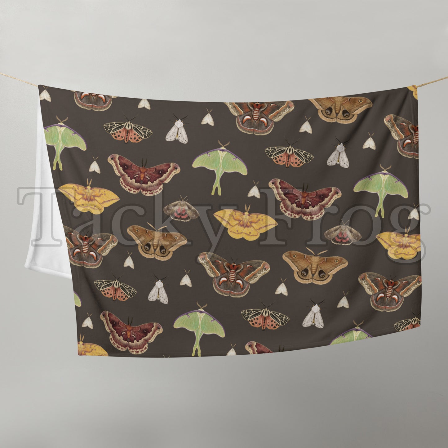 A mockup of the brown moth pattern blanket draped over a clothesline. 