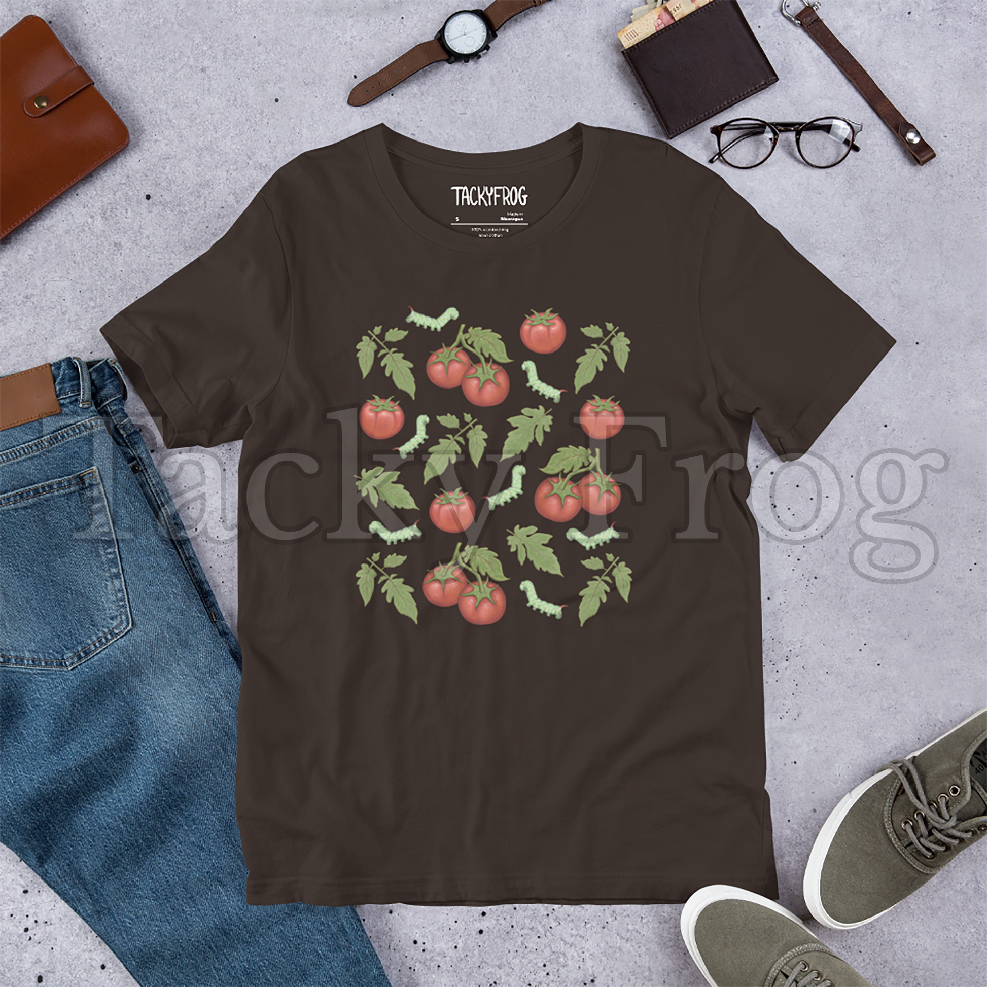 A mockup of a brown-colored tomato hornworm caterpillar t-shirt amongst some clutter.