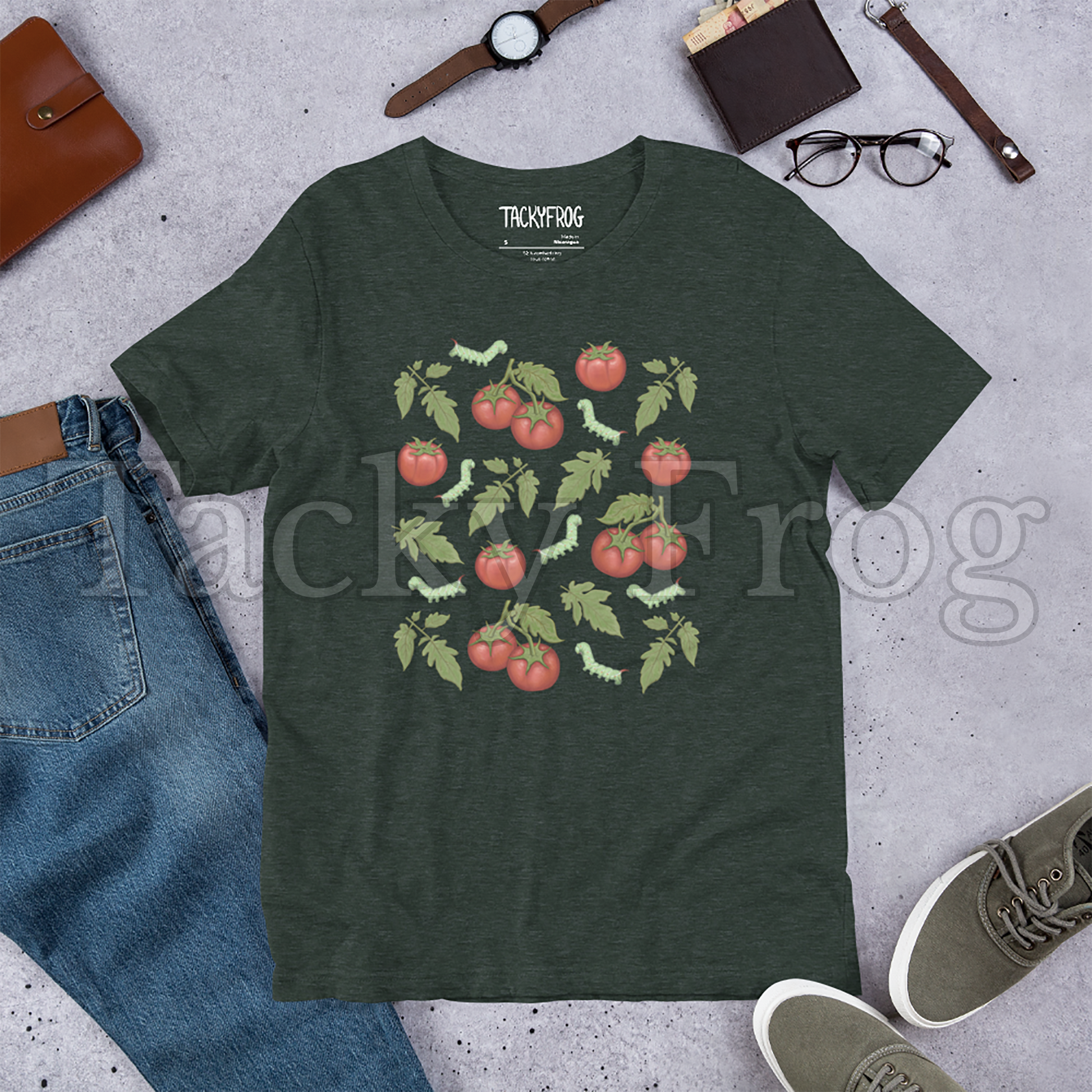 A mockup of a heather forest-colored tomato hornworm caterpillar t-shirt amongst some clutter.