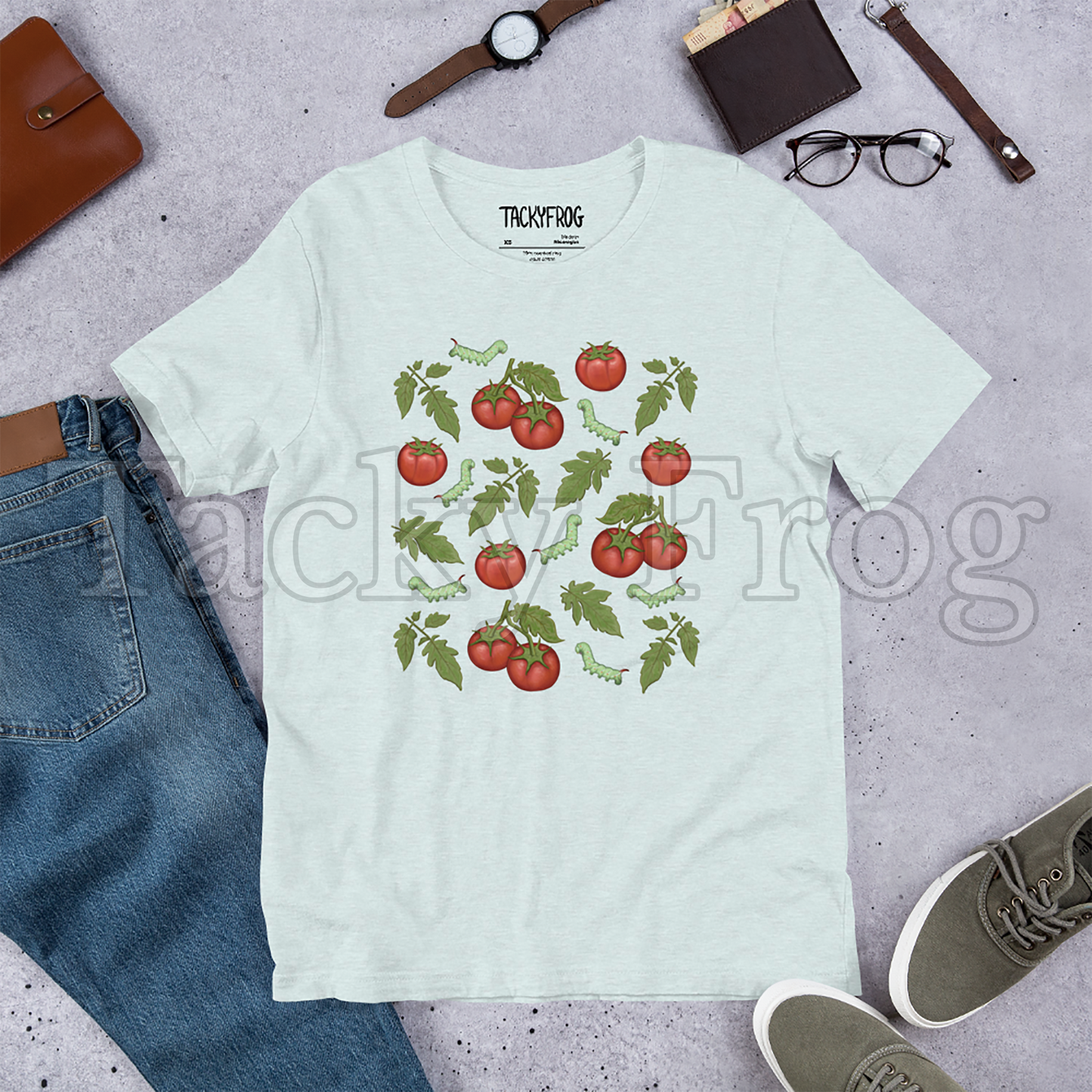 A mockup of heather prism ice blue-colored tomato hornworm caterpillar t-shirt amongst some clutter.